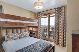 a bedroom with a wooden bed and a balcony at Edgemont 2601 - Luxury Ski-in Ski-out Condo in Steamboat Springs