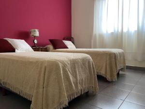 2 camas en una habitación con una pared de color rosa en Tradicional casa en Miramar Hola Sur en Miramar