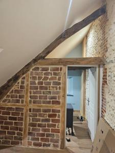 an attic room with a brick wall and an open door at Ma p'tite cabane in Neufmarché