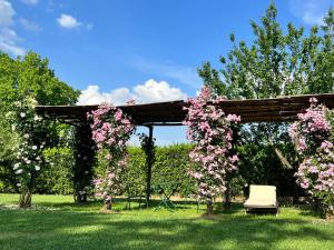 皮斯托亞的住宿－阿歐姆布拉德提格里奧農家樂，一个带粉红色花卉和长凳的木制凉亭