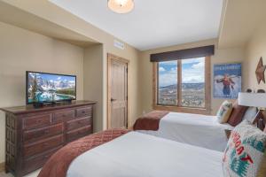 a bedroom with two beds and a flat screen tv at Edgemont 2602 - Luxury Ski-in Ski-out Condo in Steamboat Springs
