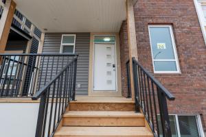 uma casa de tijolos com uma porta branca e escadas em Your Perfect 2BR Stay in SE Calgary em Calgary