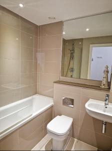 a bathroom with a toilet and a sink and a bath tub at Sea View Apartment at One Lusty Glaze in Newquay