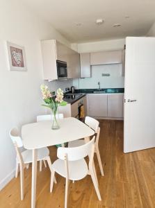 a kitchen and dining room with a white table and chairs at Sea View Apartment at One Lusty Glaze in Newquay