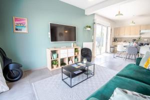 a living room with a green couch and a table at Le Gîte des Dames - 6 personnes PISCINE chauffée in La Ville-aux-Dames