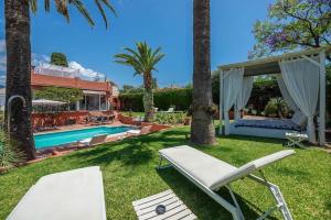un patio trasero con piscina y una silla blanca en Villa Tiphareth, en Marbella