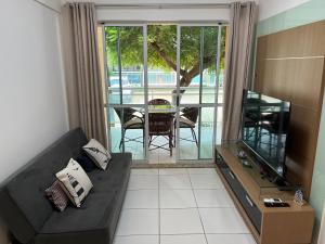 a living room with a black couch and a television at PALM BEACH Porto das Dunas, apartamento TÉRREO confortável a 350 metros Beach Park in Aquiraz