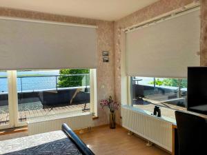 een woonkamer met 2 ramen met rolluiken bij Sunset Dream Apartment with a panoramic seaview in Haapsalu