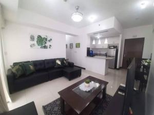 uma sala de estar com um sofá preto e uma mesa em Cubao Manhattan HEights Unit 6H Tower B, 2BR em Manila