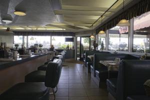 um restaurante com uma fila de cadeiras e um bar em Lamp Liter Inn em Visalia