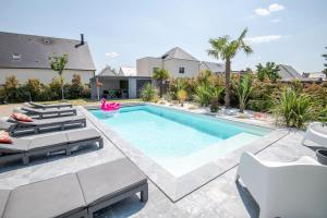 a swimming pool with chaise lounges and a pink pool noodle in at Le Gîte des Dames - 6 personnes PISCINE chauffée in La Ville-aux-Dames