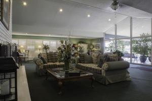 - un salon avec des canapés et une table avec des fleurs dans l'établissement Lamp Liter Inn, à Visalia