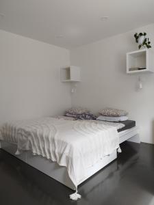 ein weißes Schlafzimmer mit einem Bett mit einer weißen Wand in der Unterkunft Courtyard Condo Twin in Liepāja