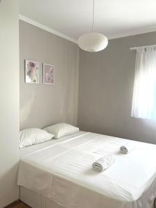 een witte slaapkamer met een bed met twee handdoeken erop bij Apartments Keko in Primošten
