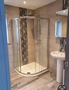 La salle de bains est pourvue d'une douche en verre et d'un lavabo. dans l'établissement Prestatyn Weekly Stay DRAGON apartment, à Prestatyn