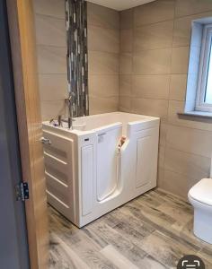 La salle de bains est pourvue d'un lavabo blanc et de toilettes. dans l'établissement Prestatyn Weekly Stay DRAGON apartment, à Prestatyn