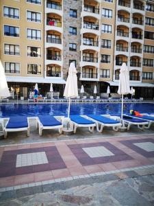 - une piscine avec des chaises et des parasols en face d'un bâtiment dans l'établissement Green Garden View, aux Sables d'or