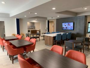 a waiting room with tables and chairs and a flat screen tv at Holiday Inn Express Hotel & Suites West Point-Fort Montgomery, an IHG Hotel in Fort Montgomery