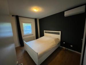 1 dormitorio con cama blanca y ventana en Nature & golf Villa, en Oosterhout