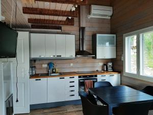 a kitchen with white cabinets and a table and a dining room at Villa Ulappa in Savonlinna