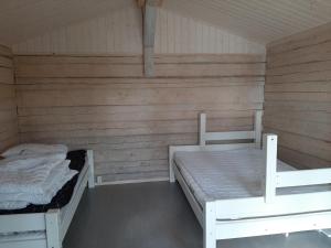 two beds in a room with wooden walls at Villa Ulappa in Savonlinna