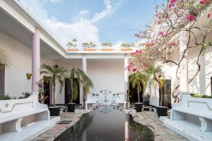 um pátio com bancos brancos, árvores e flores cor-de-rosa em HOLT Hotel De Mi Independencia Double Queen Room em Oaxaca de Juárez