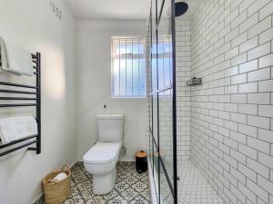 a bathroom with a toilet and a glass shower at Classy and Newly Renovated Studio in Observatory in Cape Town