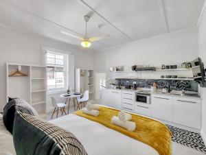 a white bedroom with a large bed and a kitchen at Classy and Newly Renovated Studio in Observatory in Cape Town