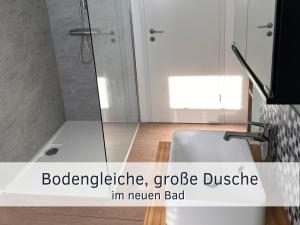 La salle de bains est pourvue d'une douche et d'un lavabo blanc. dans l'établissement Lotsenbude Fehmarn, perfekt für Familien & Paare, Nähe Hafen Burgstaaken, à Burg 28 autres photos