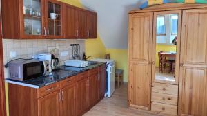 eine Küche mit Holzschränken und einer Mikrowelle in der Unterkunft Villa Zlata Praha in Hévíz