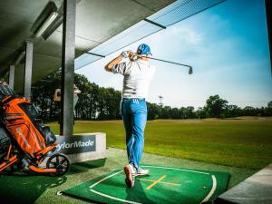 um homem a balançar um taco de golfe num campo de golfe em Nature & golf Villa em Oosterhout