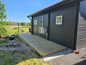 a black house with a wooden deck and a grill at Attefallshus Nära Havet Norranäs in Varberg