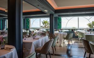 un restaurante con mesas y sillas blancas y ventanas en Résidence Les Flamants Roses, en Canet-en-Roussillon
