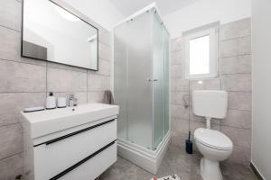 a white bathroom with a sink and a toilet at Mariva Apartments in Lopar