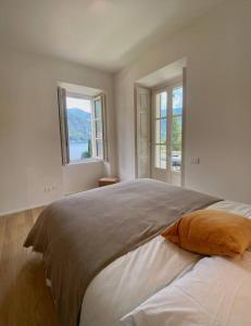 a bedroom with a large bed with two windows at Laglio Charlie's House Lake View in Laglio