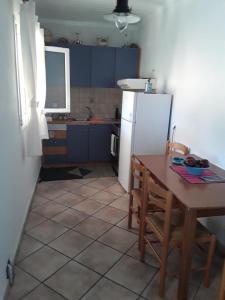 uma cozinha com uma mesa e um frigorífico branco em Theros Apartment em Spartokhórion