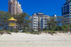 a beach with tall buildings and a yellow lifeguard tower at La Grande Apartments in Gold Coast