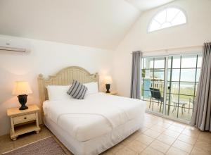 a bedroom with a white bed and a balcony at Willowbank Resort in Somerset