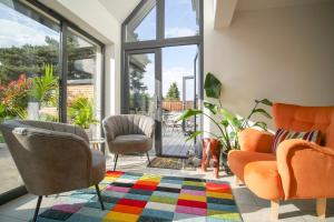 a living room with orange chairs and a colorful rug at Pinewood Cottage Apartment & B&B Inverness in Inverness