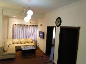 uma sala de estar com um sofá e um relógio na parede em Luxury 2BR Family Apt/Wi-Fi / Netflix em Islamabad