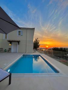 een zwembad voor een huis met een zonsondergang bij Iliana Exclusive Villa - Private Pool - Walking Distance To Beach in Porto Cheli