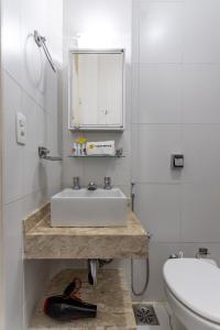 a white bathroom with a sink and a toilet at Conforto em Ipanema - 2 quadras da praia - VP604 Z1 in Rio de Janeiro