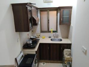 a small kitchen with wooden cabinets and a sink at Luxury 2BR Family Apt/Wi-Fi / Netflix in Islamabad