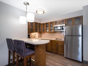 a kitchen with a stainless steel refrigerator and wooden cabinets at Staybridge Suites - Sioux City Southeast by IHG in Sioux City