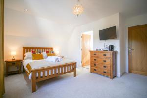 a bedroom with a bed and a dresser and a television at Pinewood Cottage Apartment & B&B Inverness in Inverness