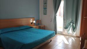a bedroom with a blue bed and a sliding glass door at B&B Cristina in Torricella