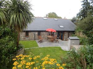 a garden with a table and a red umbrella at Whitewell Barn in Swansea