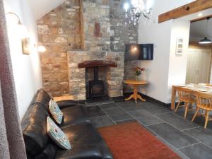 a living room with a leather couch and a fireplace at Whitewell Barn in Swansea