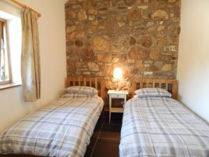 two beds in a room with a stone wall at Whitewell Barn in Swansea