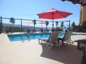 a pool with two chairs and a red umbrella at Sultana Farm - Private Pool Villa near Amman in Bayyūḑah